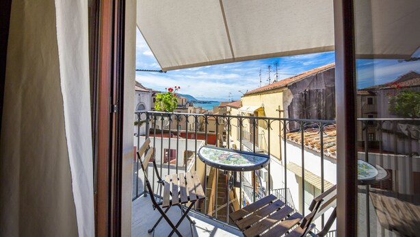 Un balcón con una mesa y sillas, vista a edificios y cielo despejado.