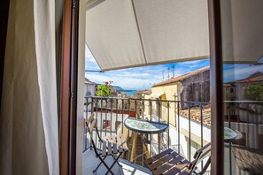 Un balcón con una mesa y sillas, vista a edificios y cielo despejado.