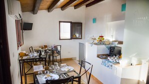 Un comedor con una mesa lista para cuatro personas, una cocina equipada con refrigerador y microondas, y una ventana con vistas al exterior.