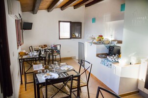Un comedor con una mesa lista para cuatro personas, una cocina equipada con refrigerador y microondas, y una ventana con vistas al exterior.