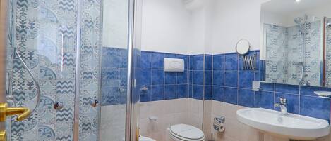 Une salle de bain avec une douche à parois de verre, des toilettes, un lavabo et un banc en bois.