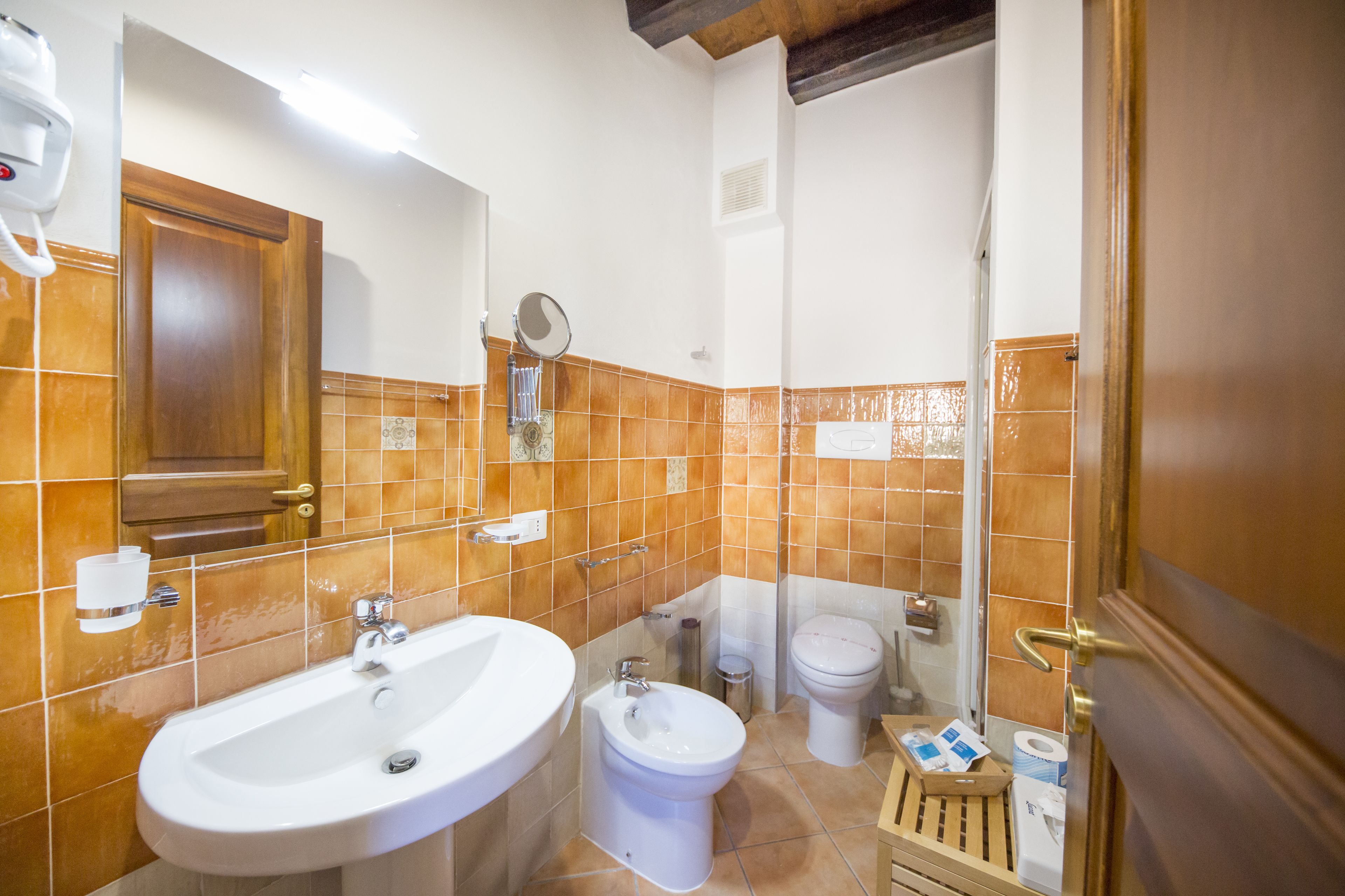 Ein Badezimmer mit Waschbecken, Bidet, Toilette und einer Holztür.