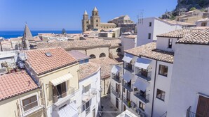 Un pueblo costero con edificios de tejas de color terracota, una iglesia destacada con campanario, y una vista despejada del mar.