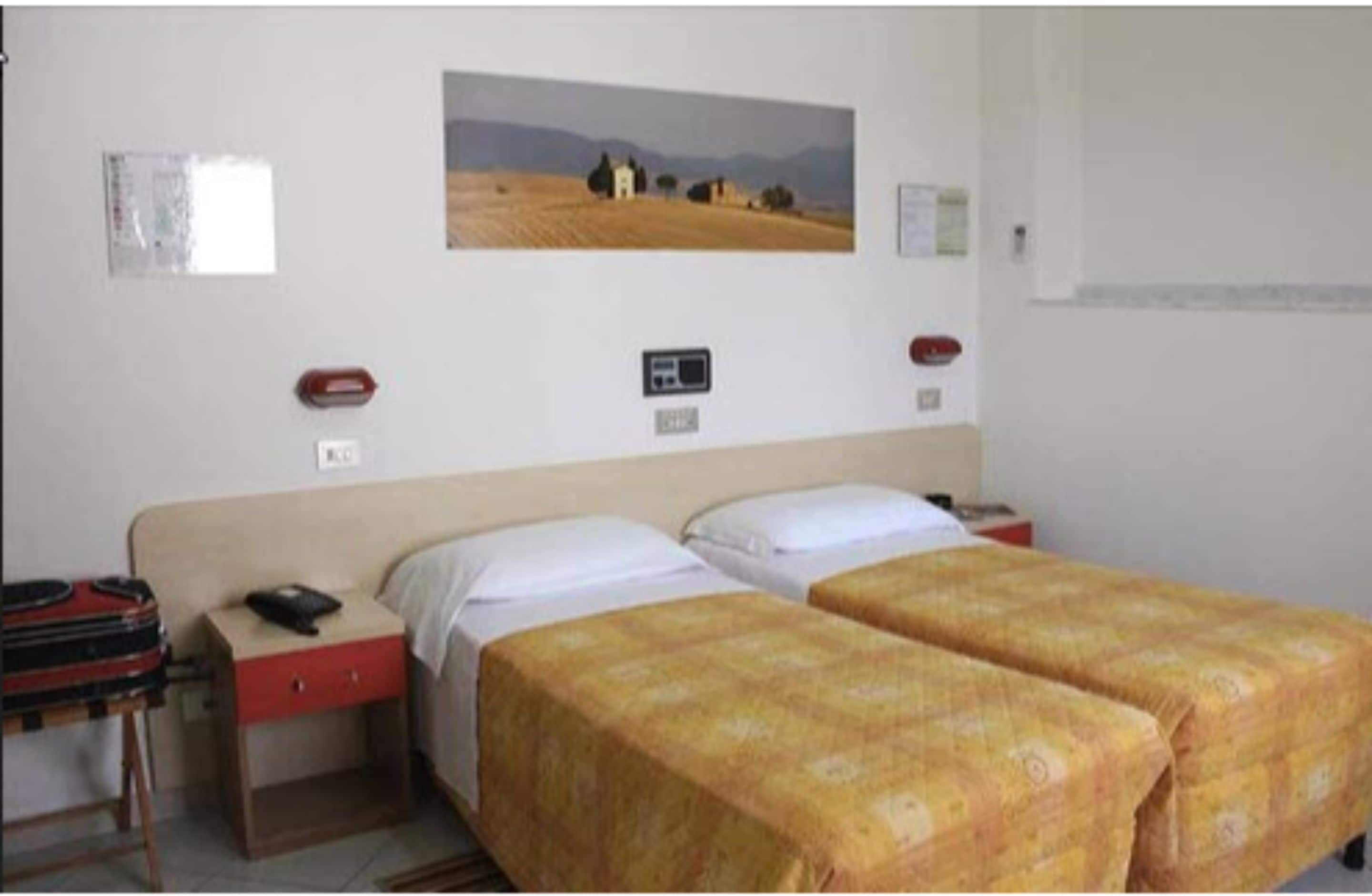 Una habitación con dos camas, un escritorio con teléfono y un cuadro colgado en la pared.