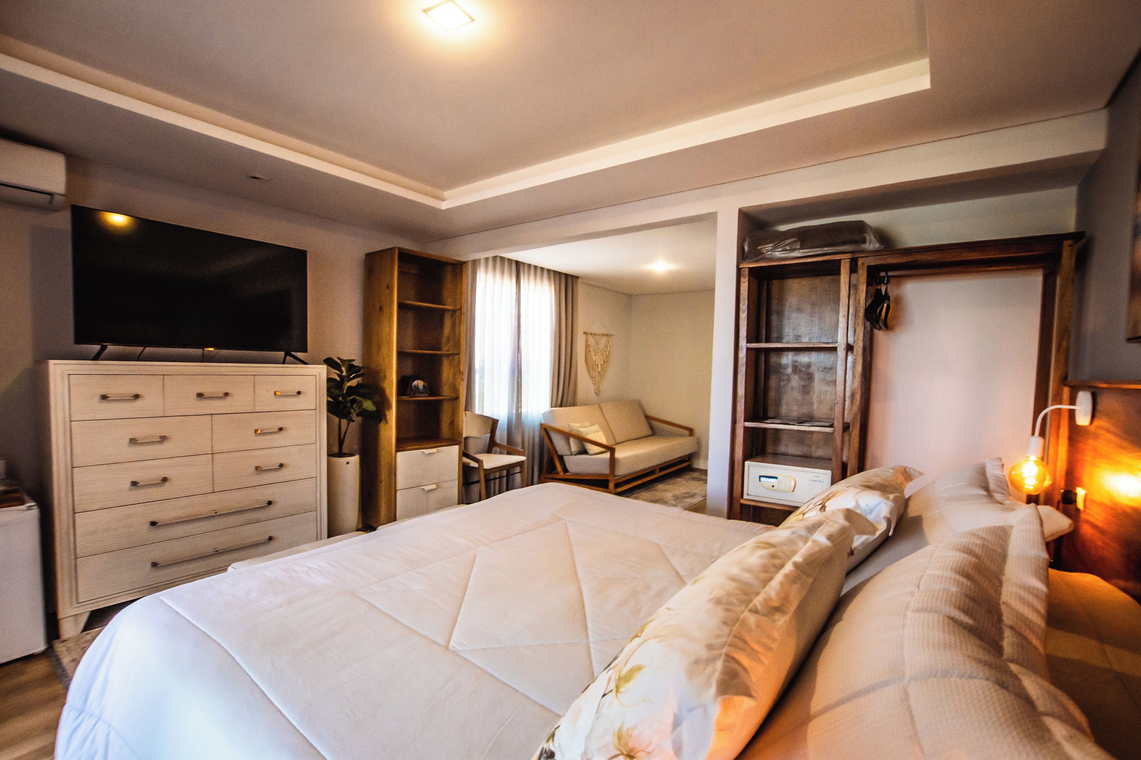 A modern hotel room with a large bed, a television, a wardrobe, a desk, and a chair.