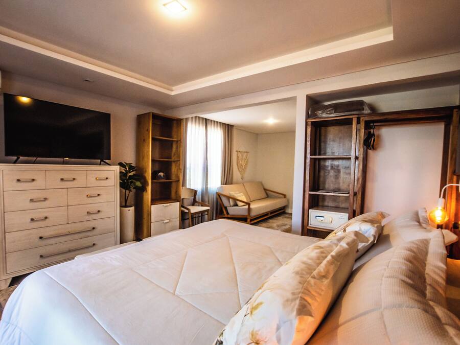A modern hotel room with a large bed, a television, a wardrobe, a desk, and a chair.