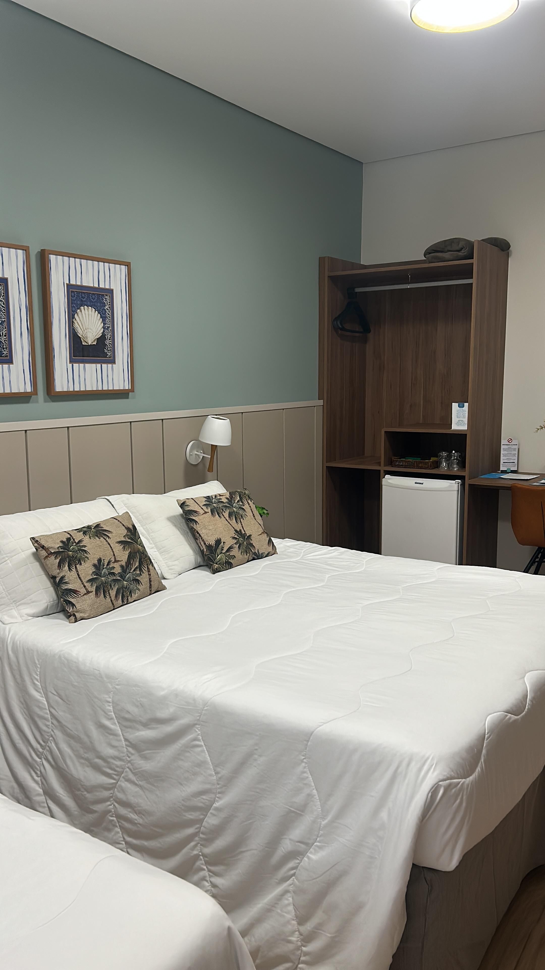 A hotel room with a bed, a wardrobe, a desk, and a refrigerator.
