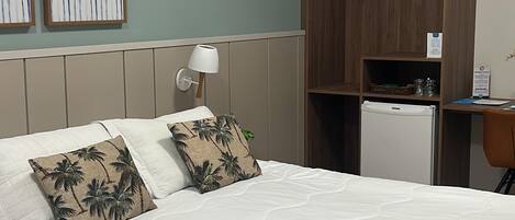 A hotel room with a bed, a wardrobe, a desk, and a refrigerator.