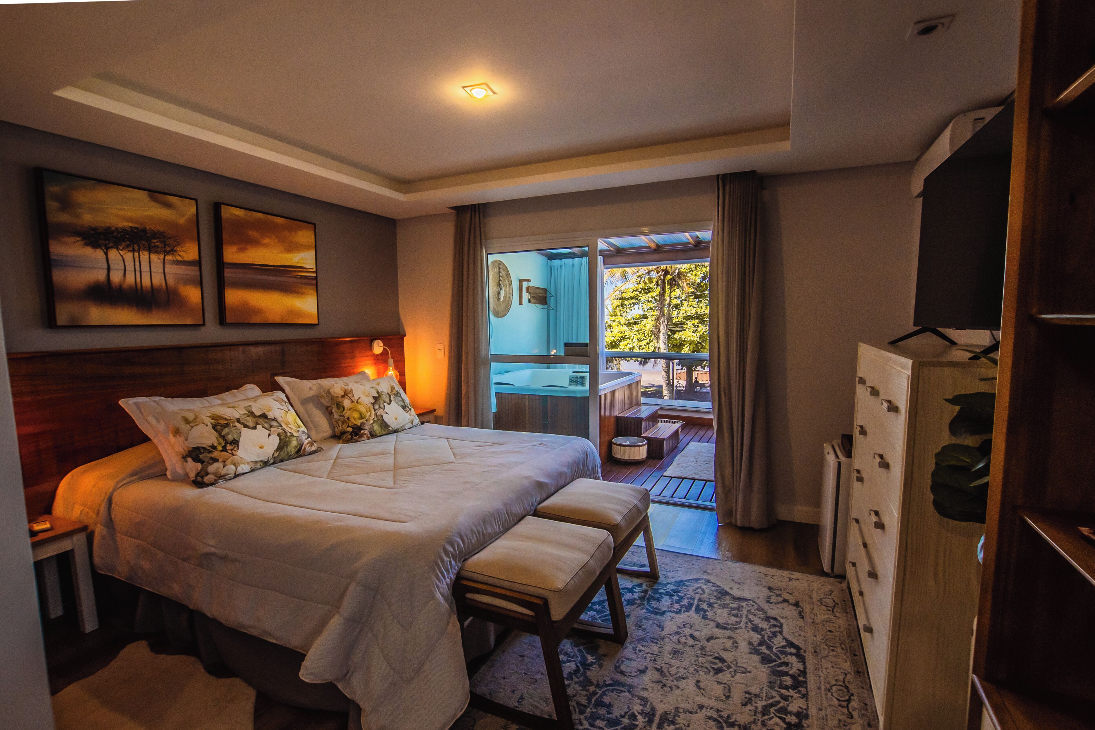 A bedroom with a large bed, a wooden headboard, and a view of a balcony.