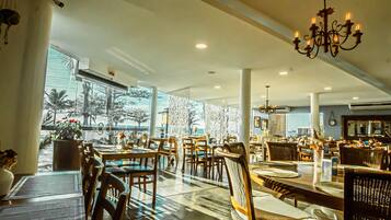 En rummelig restaurant med høje lofter, moderne belysning og store vinduer med udsigt til palmer.