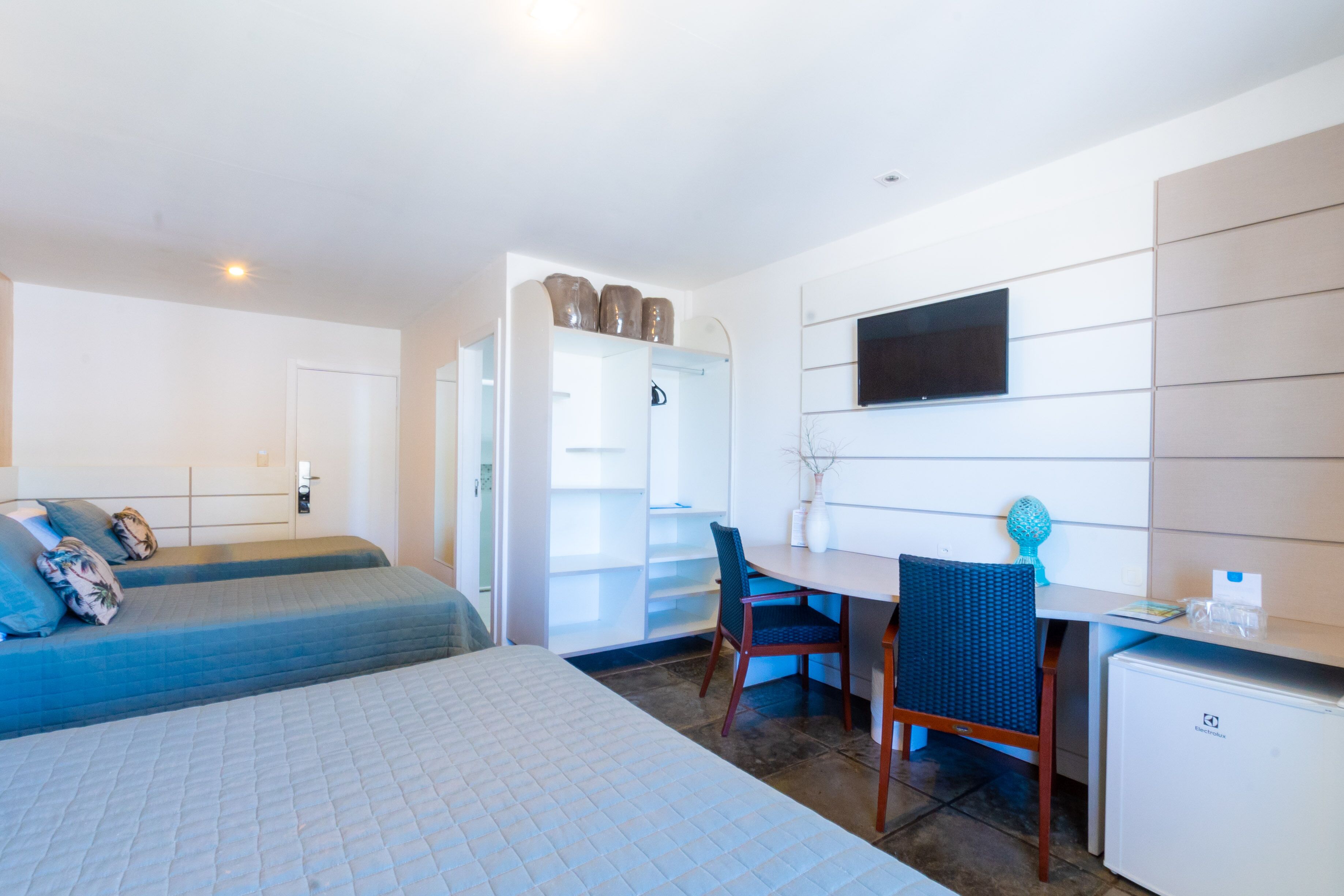 Ein Hotelzimmer mit einem Bett, einem Schreibtisch, einem Sessel, einem Fernseher und einem kleinen Kühlschrank.