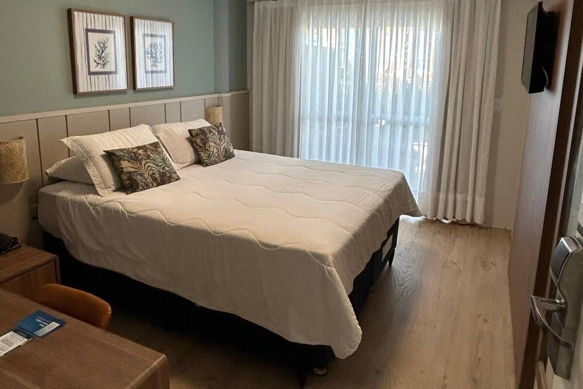 Une chambre d’hôtel avec un lit, un bureau et une fenêtre avec des rideaux.