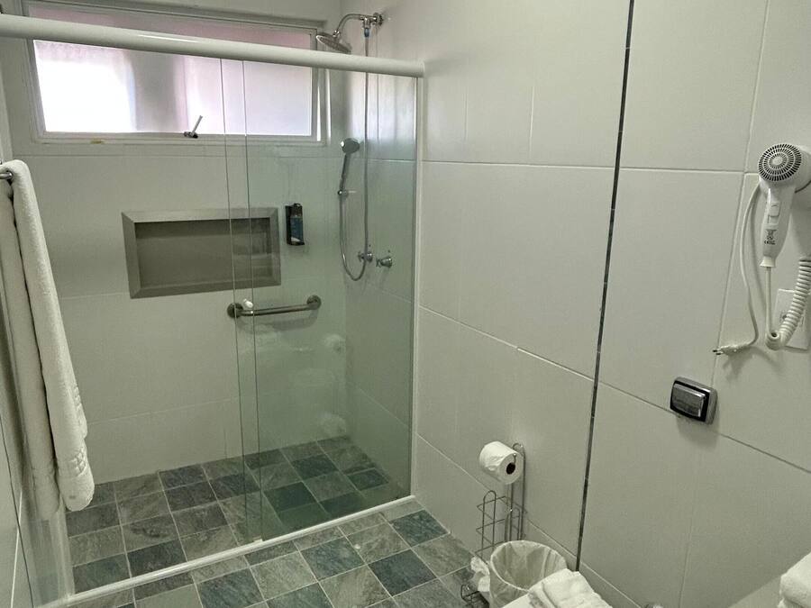 Un baño moderno con ducha envuelta en vidrio, inodoro con tapa y perchero para toallas.