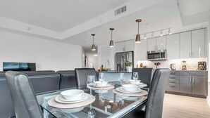 A modern dining area with a glass table, black chairs, and a kitchen in the background. - Fully Furnished Apartment in Washington near Logan Circle (Washington)