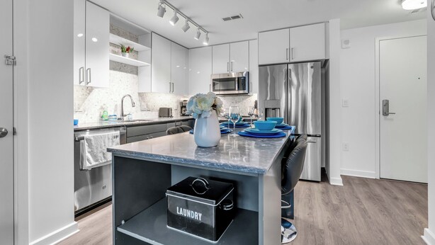 A modern kitchen with white cabinets, stainless steel appliances, and a marble countertop. - Fully Furnished Apartment in Washington near Logan Circle (Washington)