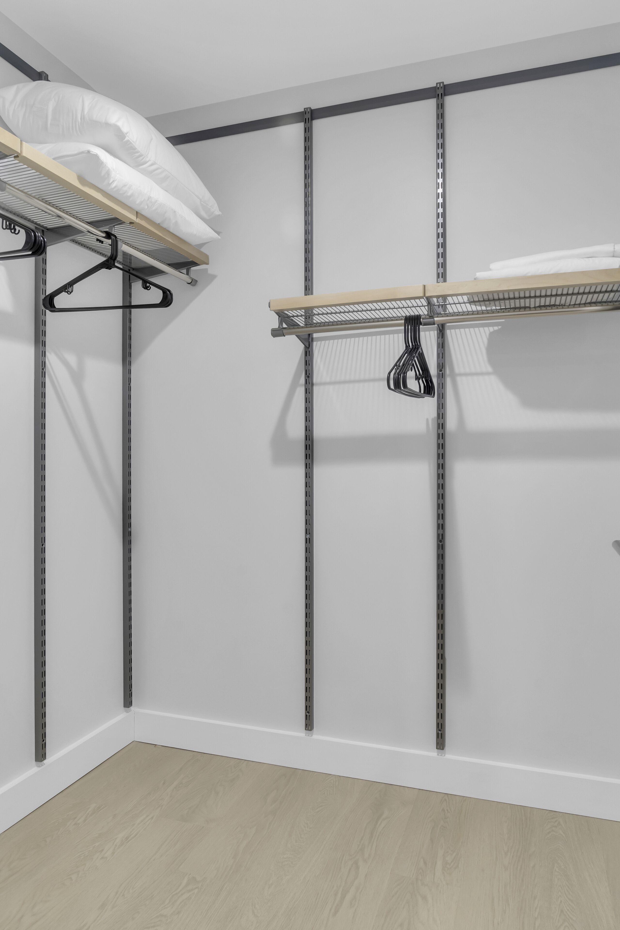 A storage closet with metal shelving and hanging space for clothes.