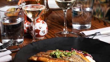 A dining table with a fish dish, wine glasses, and a vase with flowers.