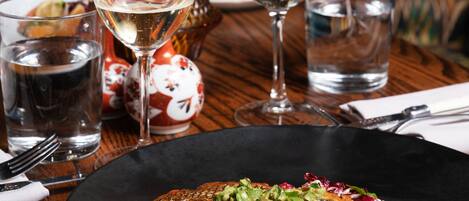 A dining table with a fish dish, wine glasses, and a vase with flowers.