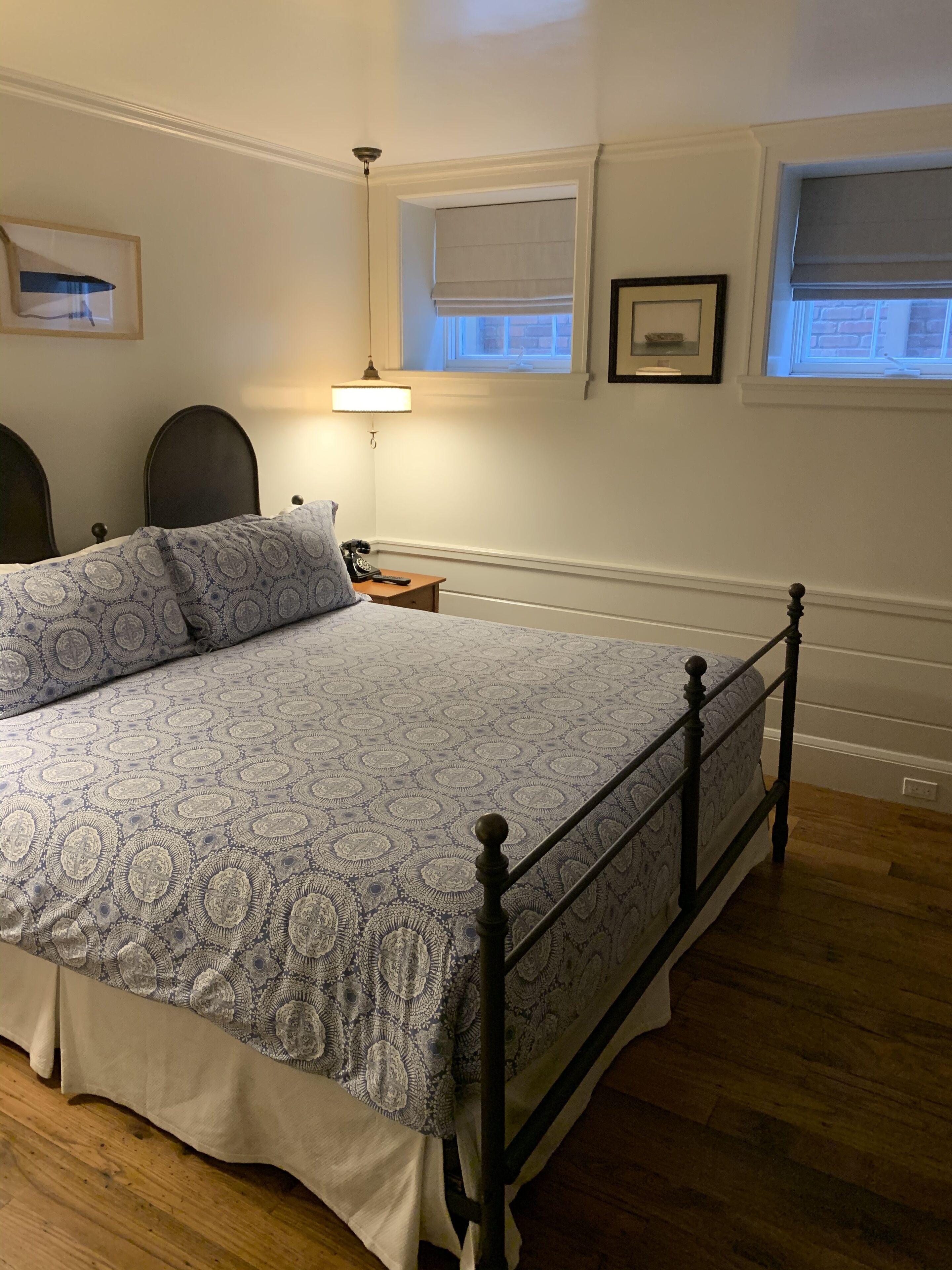 Un dormitorio con cama, piso de madera y ventana con persianas.