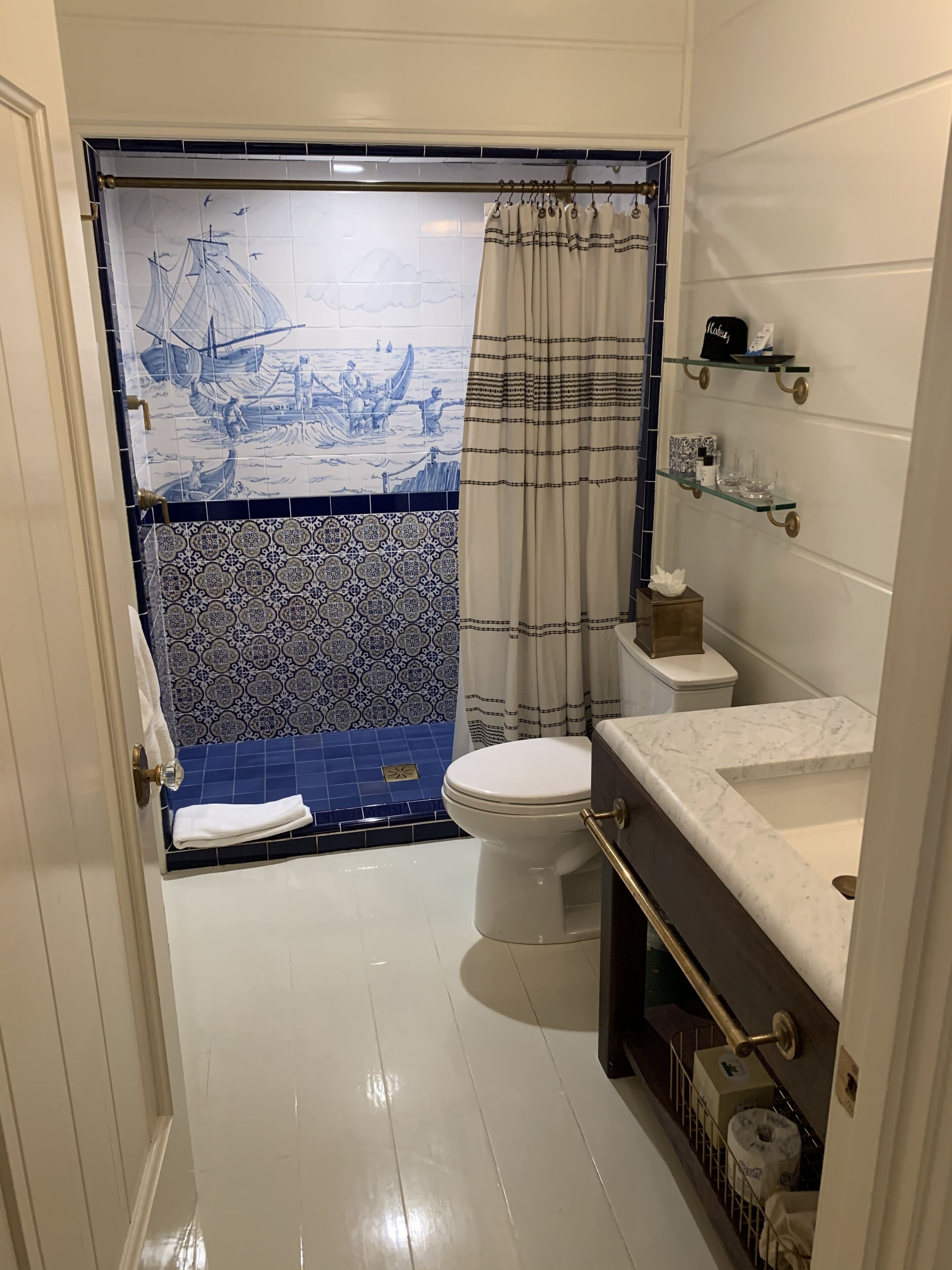 A bathroom with a toilet, a sink, and a shower curtain with a nautical design.