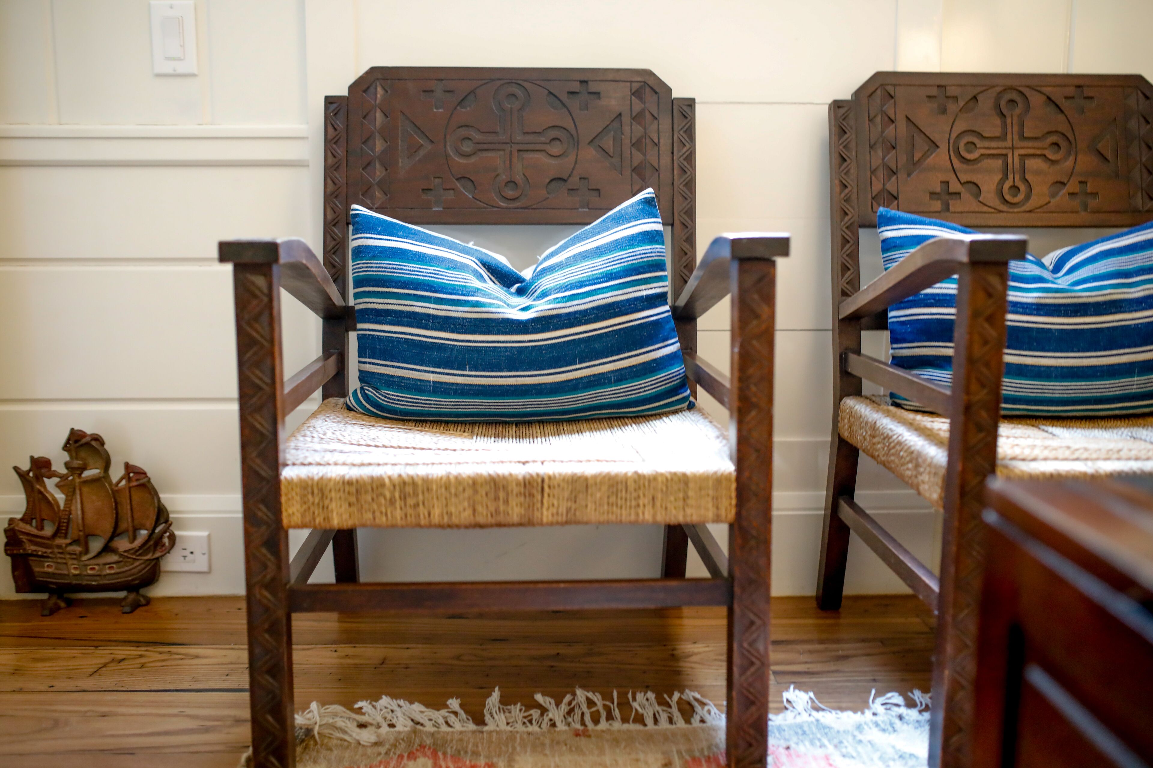 Deux chaises en bois, dotées d’assises et de dossiers en osier, chacune agrémentée d’un coussin à rayures bleues et blanches.