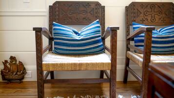 Deux chaises en bois, dotées d’assises et de dossiers en osier, chacune agrémentée d’un coussin à rayures bleues et blanches.
