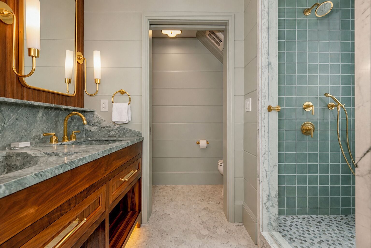 Un baño con lavamanos de mármol, detalles dorados y ducha con revestimiento de diseño de cuadrícula.