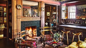 A cozy room with a fireplace, wooden furniture, and a bookshelf. - Greydon House (Nantucket)