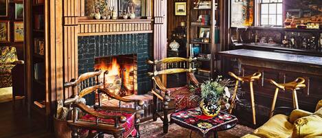 A cozy room with a fireplace, wooden furniture, and a bookshelf.