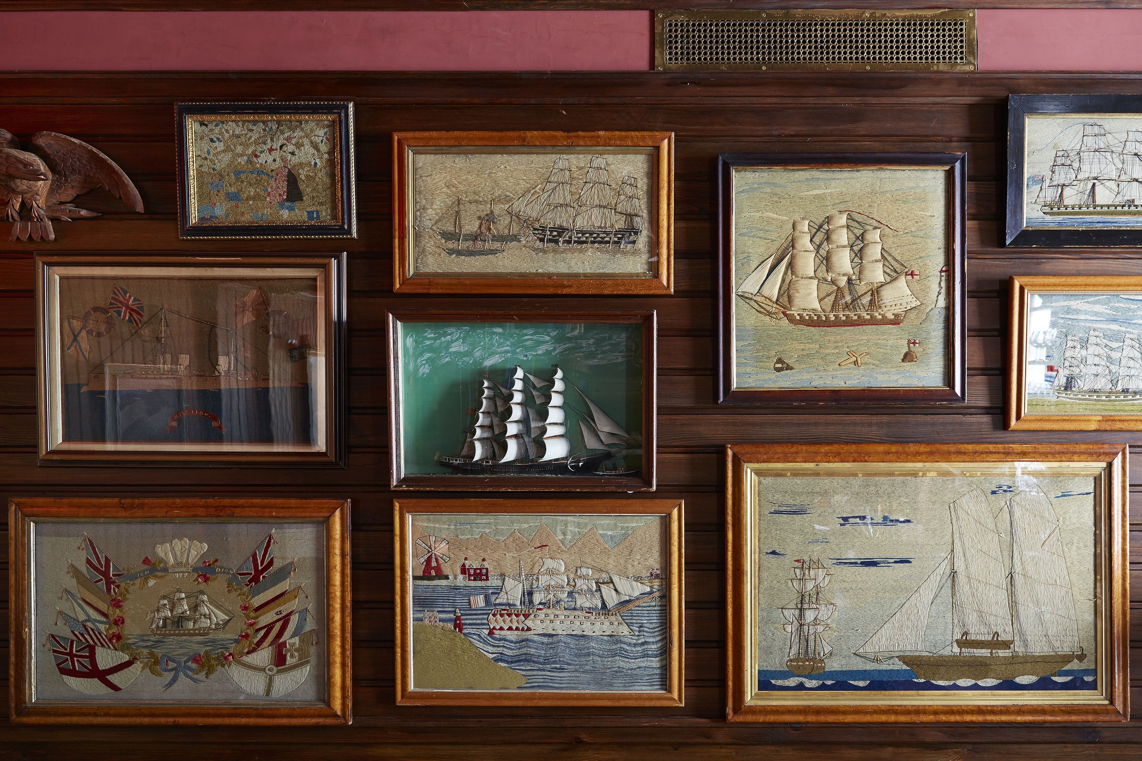 Eine Wand mit mehreren gerahmten Kunstwerken, die maritime Szenen zeigen.