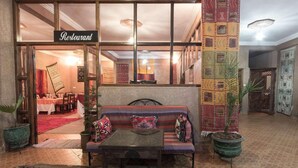 Un restaurante con decoración tradicional, que incluye un sofá, una mesa y alfombras estampadas.