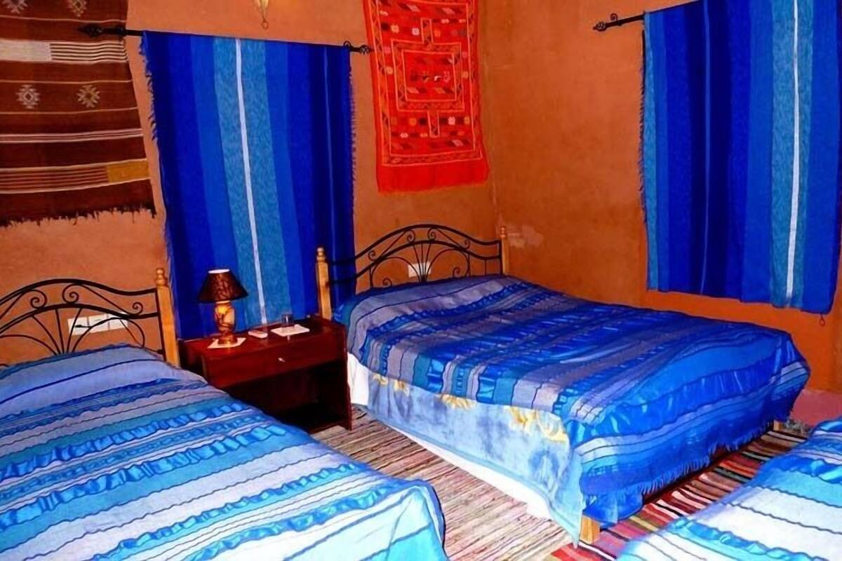 A room with two beds, a nightstand, and a red decorative item on the wall.