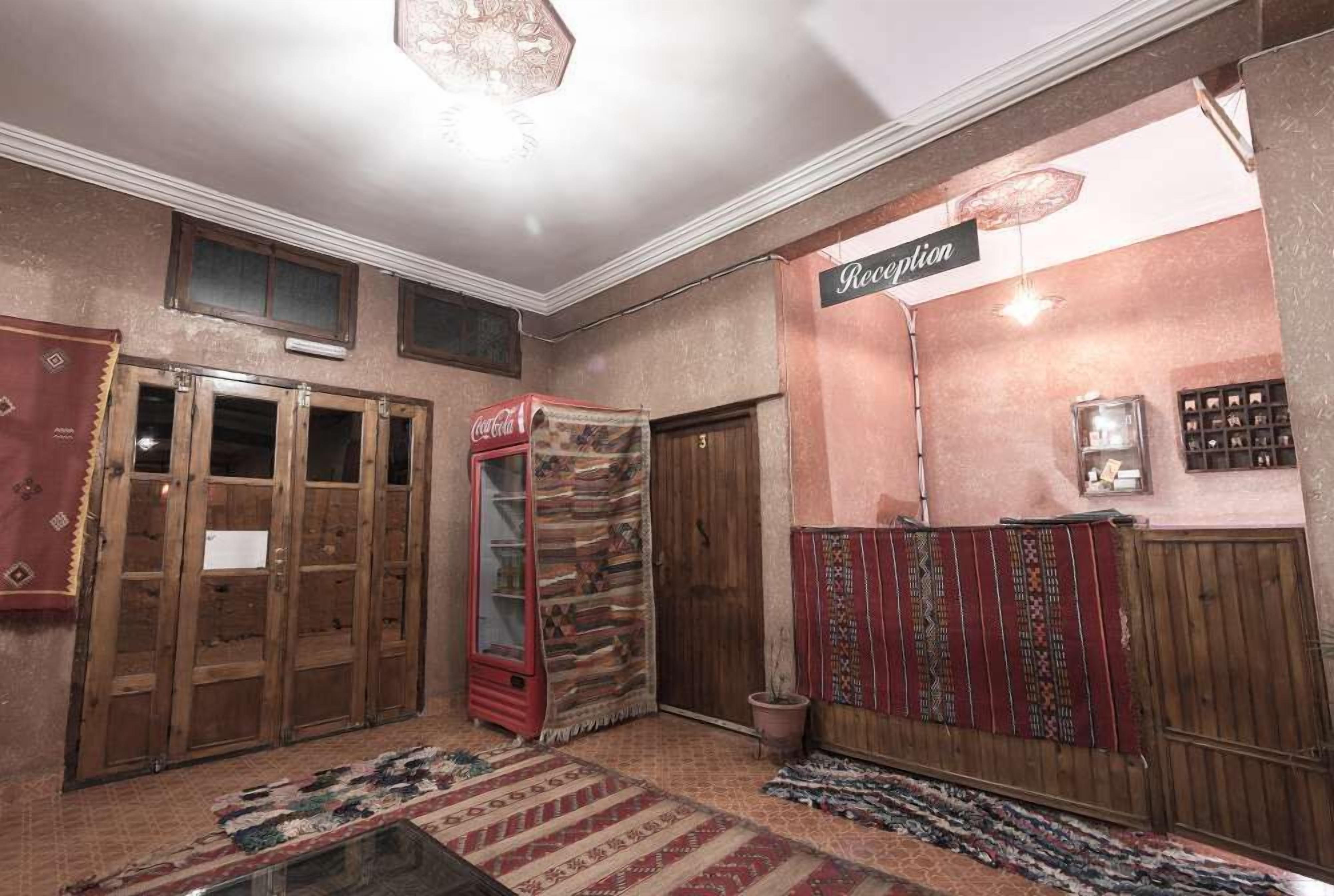 A reception area with a Coca-Cola refrigerator, a reception desk, and a wall-mounted sign.