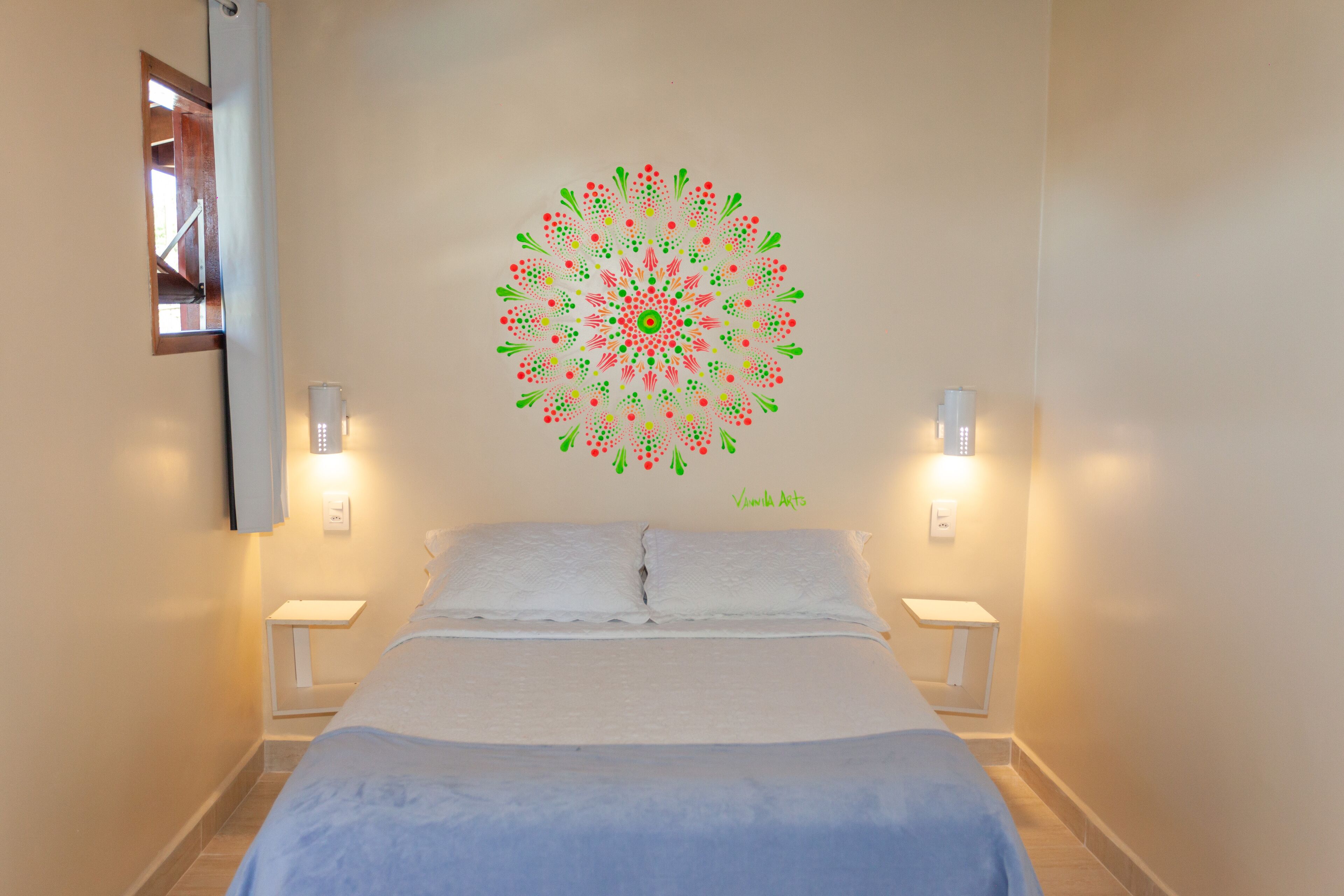 A bedroom with a bed, two bedside tables, and a wall decoration.