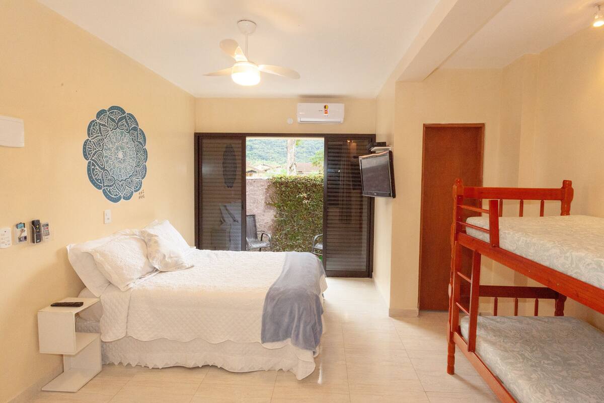 A bedroom with a bed, a ceiling fan, a television, and a bunk bed.