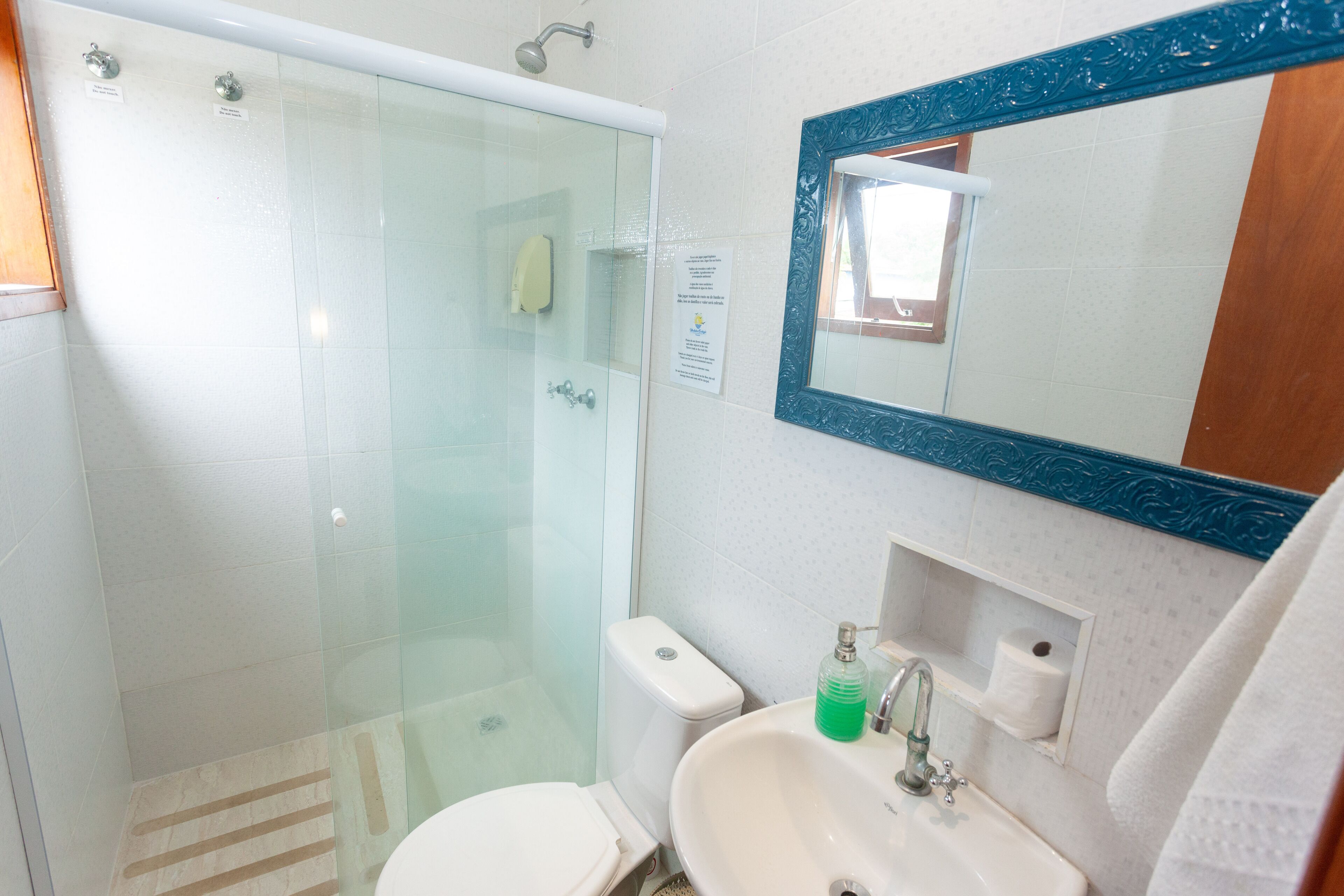 Une salle de bain avec une douche à parois de verre, des toilettes, un lavabo avec un miroir au-dessus et une serviette accrochée au mur.