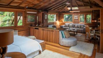 Cozy retreat with a large bed, seating area, and desk, offering a peaceful view of the surrounding greenery.