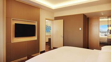 Une chambre d’hôtel avec un grand lit, un téléviseur à écran plat fixé au mur et une vue sur la ville par la fenêtre.