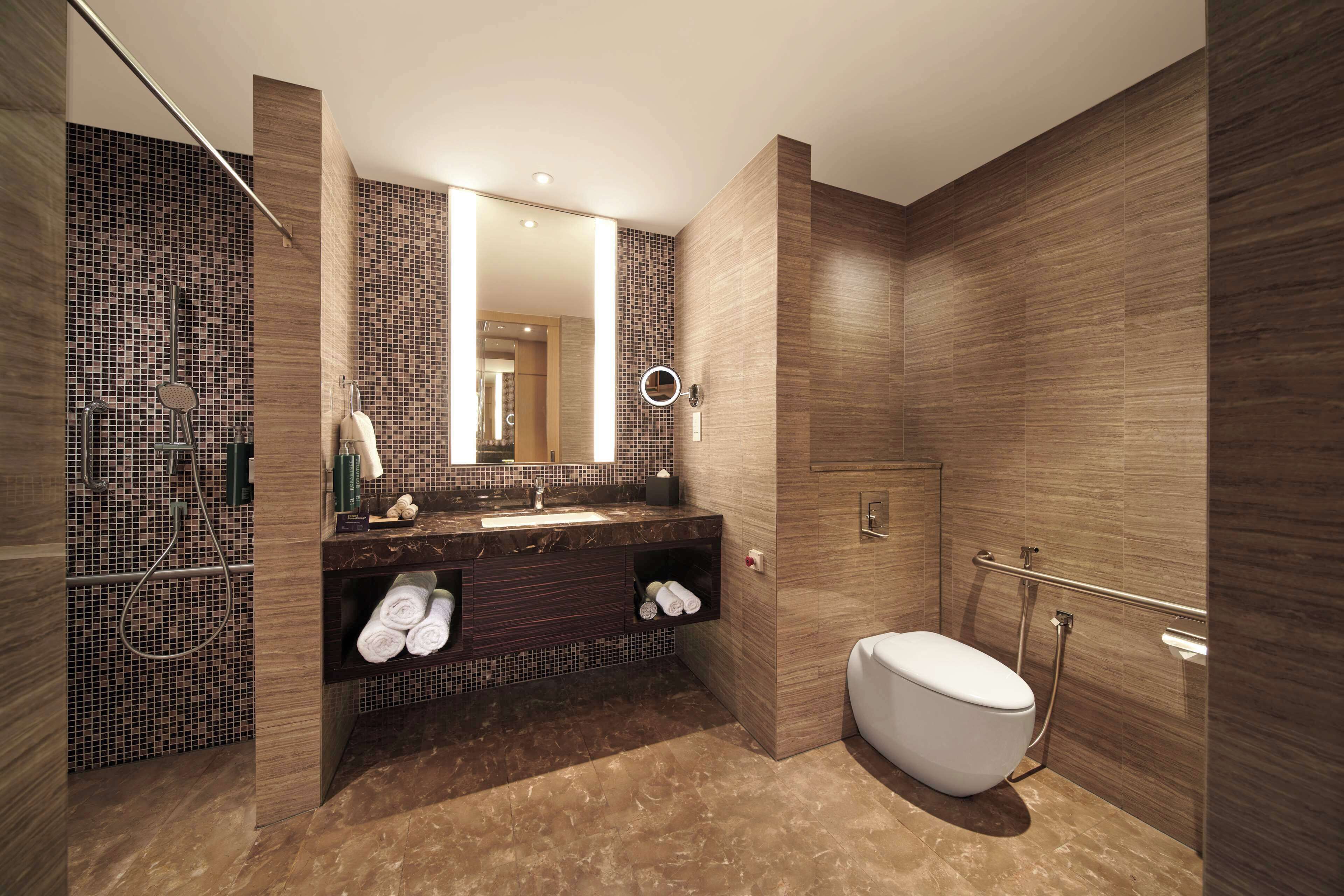 Un baño moderno con un espejo grande, un lavabo y un inodoro.