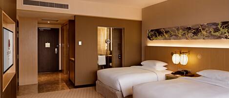 Une chambre d’hôtel avec deux lits, un grand miroir, une table de chevet avec une lampe et une œuvre d’art accrochée au mur.