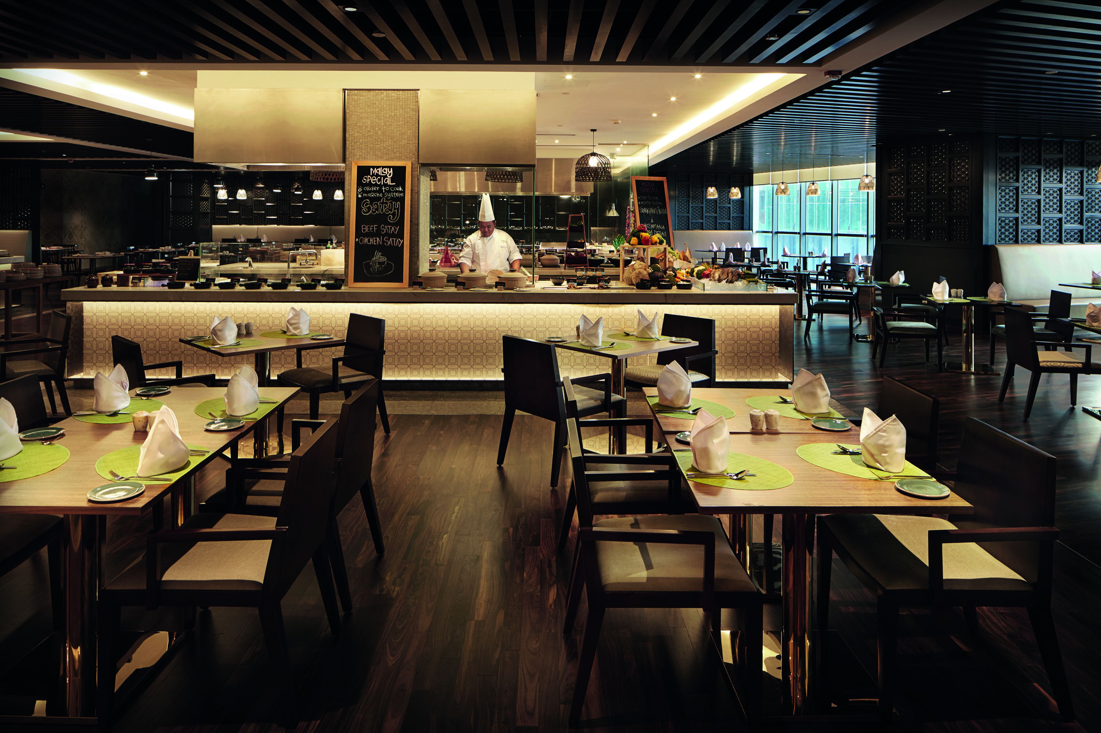 A modern restaurant with a central counter, multiple dining tables, and chairs.
