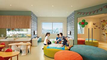 A children's play area with colorful seating, a large window with a city view, and a kitchen area with wooden cabinets.