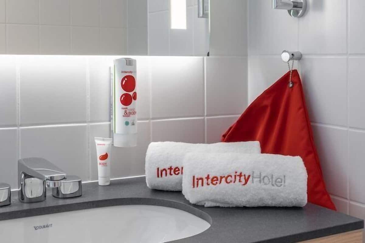 A modern bathroom with a white sink, a mirror, and toiletries.