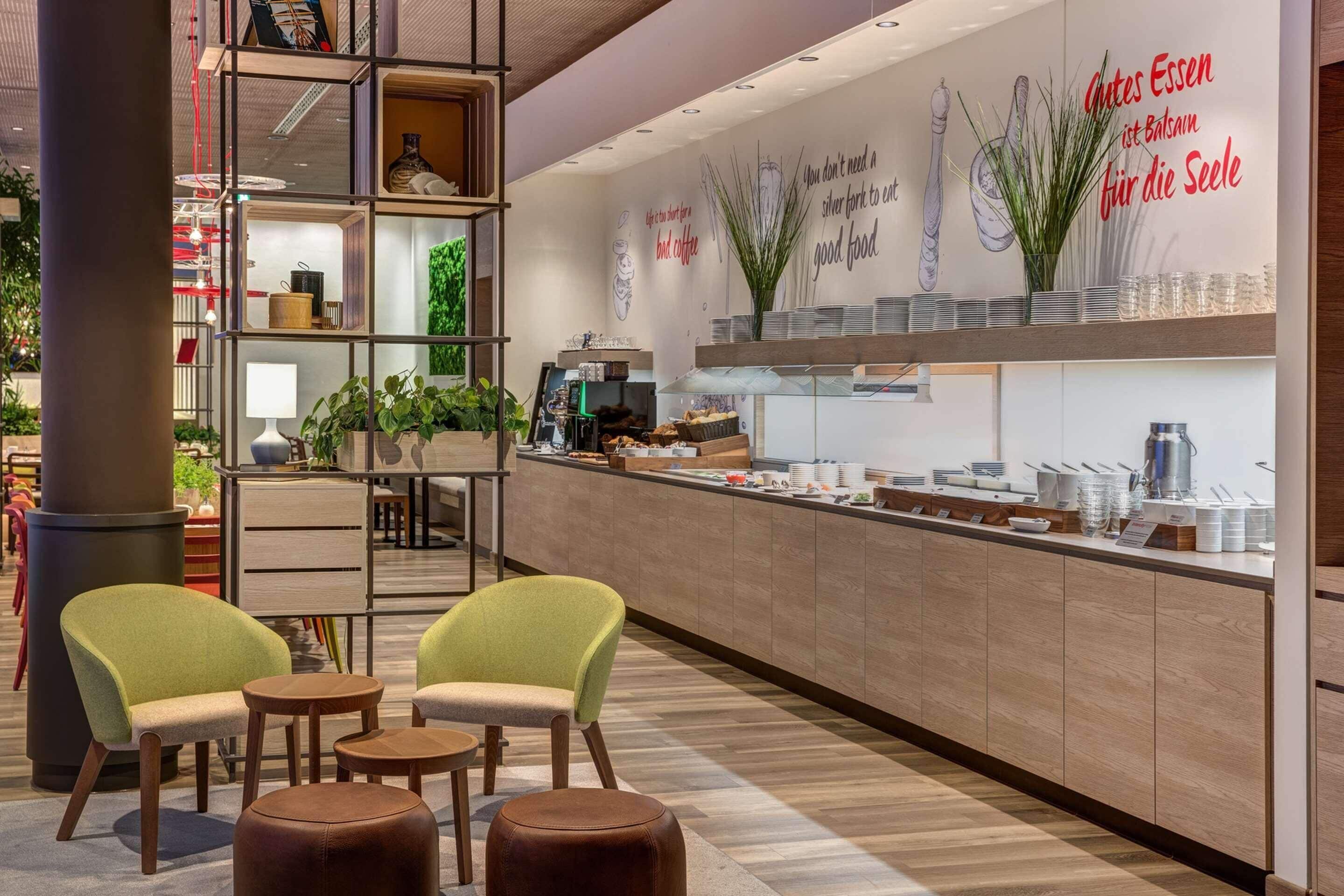 Una cafetería moderna con mostrador, zona de estar y decoración mural.
