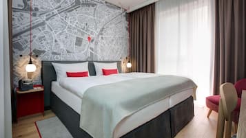 Una habitación de hotel moderna con una cama grande, una silla roja, un mapa en la pared y una mesita de noche con un teléfono.