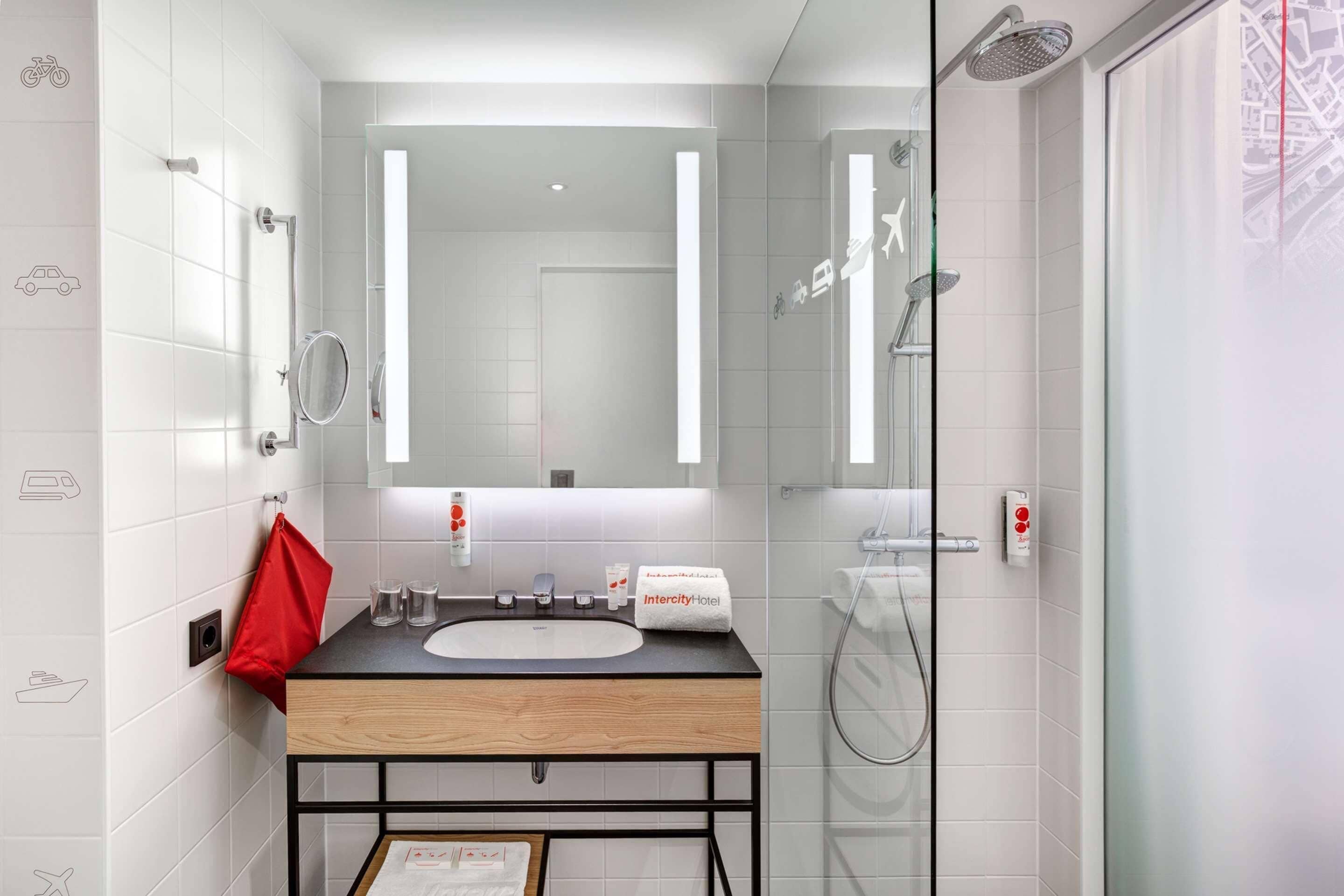 A modern bathroom with a wooden vanity, a large mirror, and a glass shower enclosure.