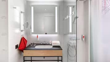A modern bathroom with a wooden vanity, a large mirror, and a glass shower enclosure.