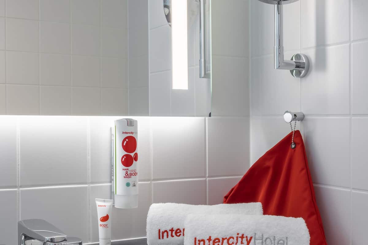 A bathroom with a white sink, a mirror, and toiletries.