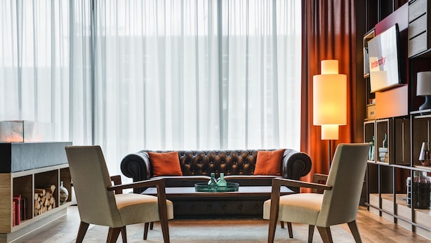 A modern living room with a leather sofa, two armchairs, a coffee table, and a bookshelf. - IntercityHotel Duisburg (Duisburg)