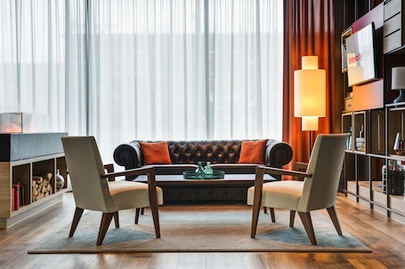 A modern living room with a leather sofa, two armchairs, a coffee table, and a bookshelf.